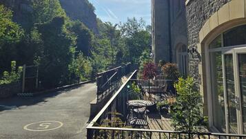 A building with a stone facade, a balcony with outdoor seating, and a clear sky.