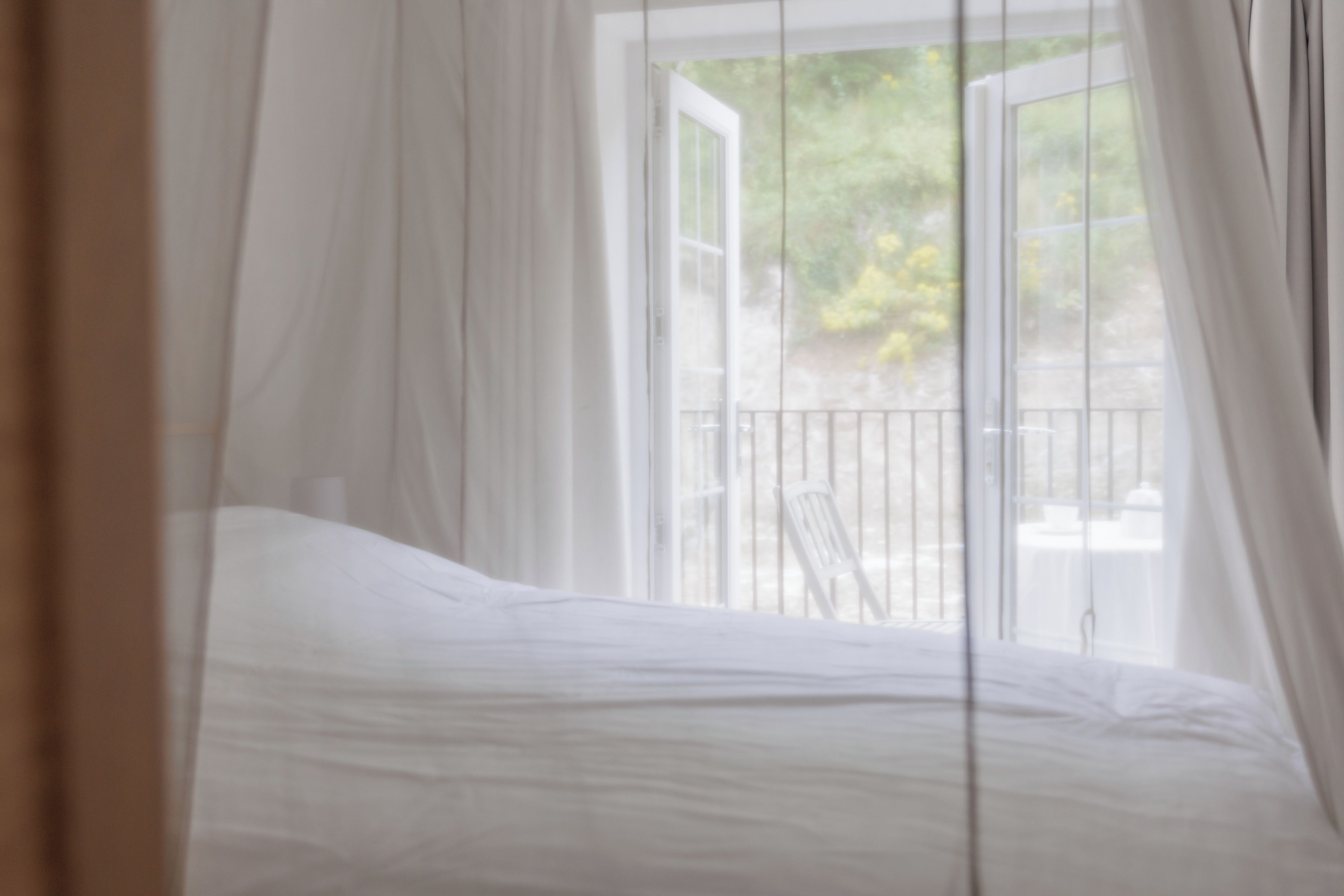 A bedroom with a bed, a window with curtains, and a view of the outdoors.