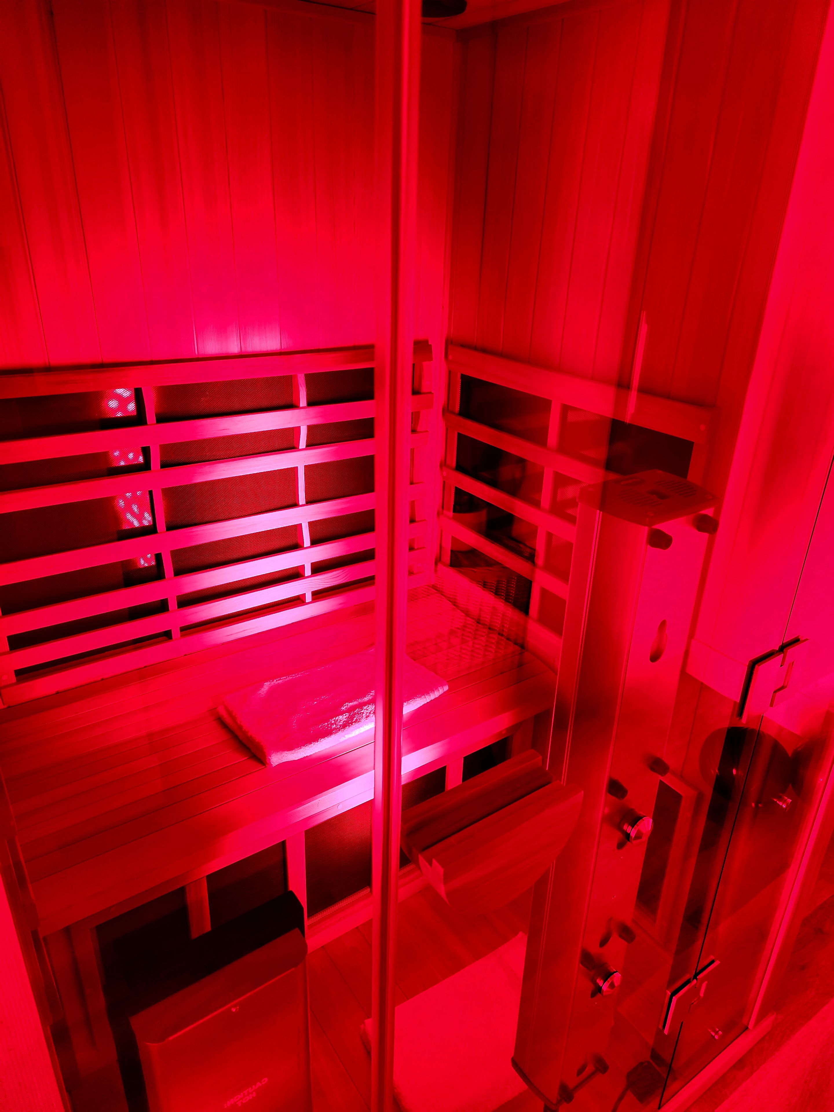 A red-lit room with bunk beds and a small desk.