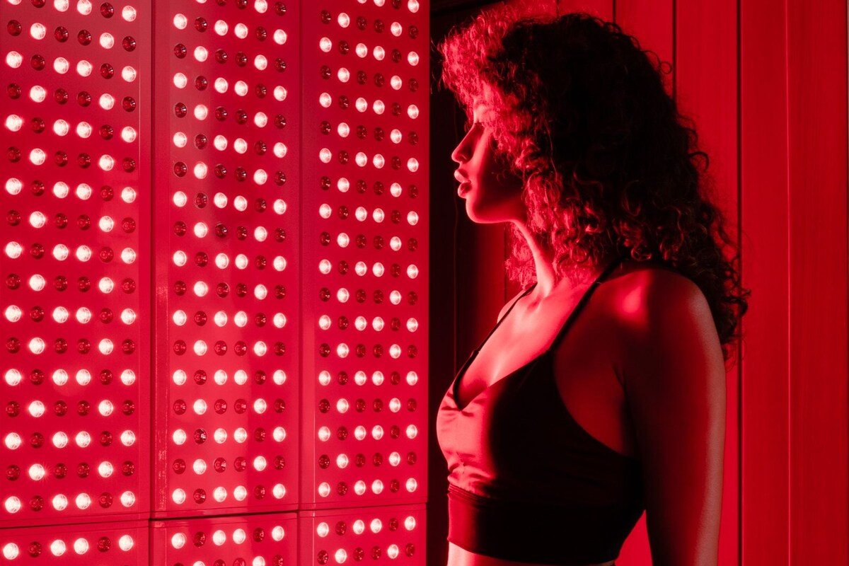 A person standing next to a wall with a pattern of lights.