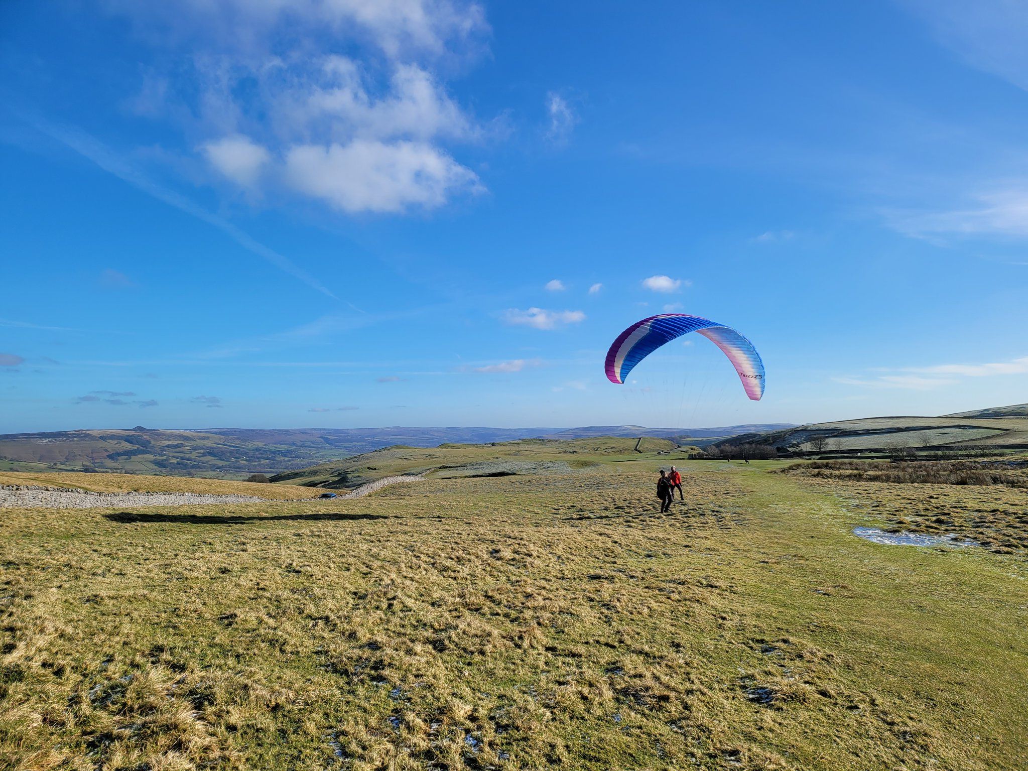 A wide-open field with a person paragliding in the distance.