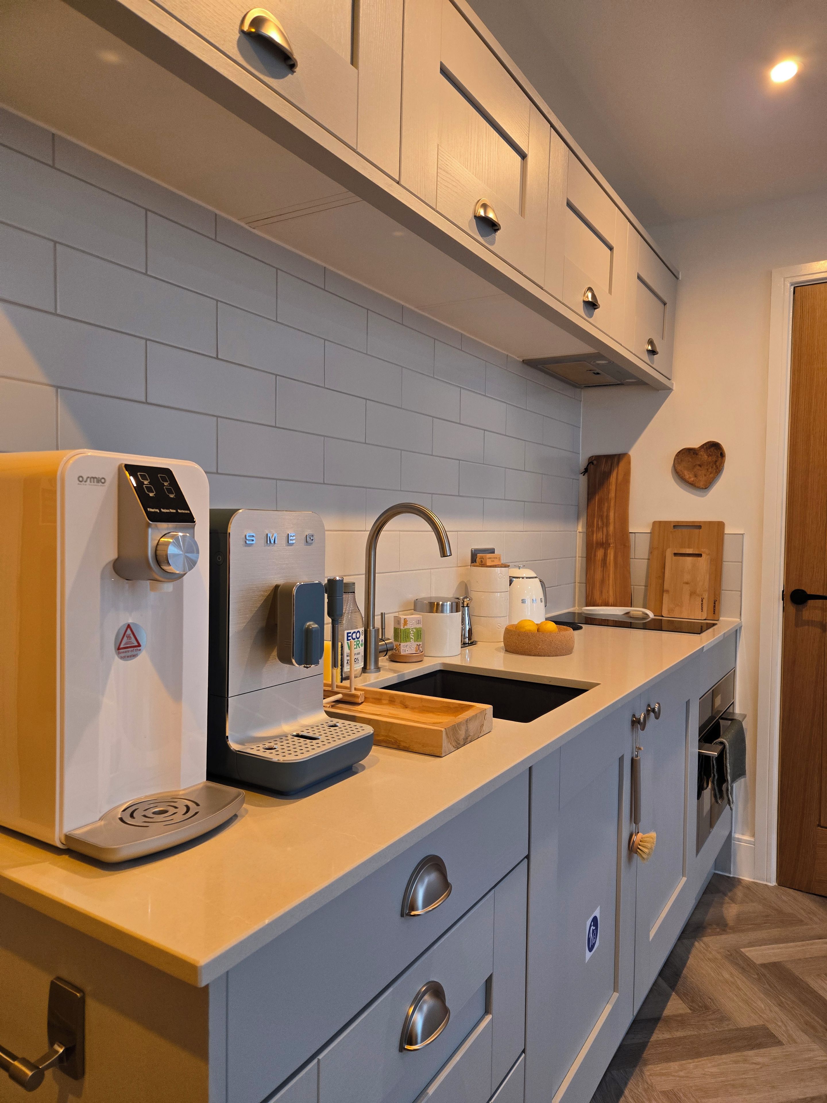 Una cocina moderna con cafetera integrada, un lavamanos y armarios de madera.