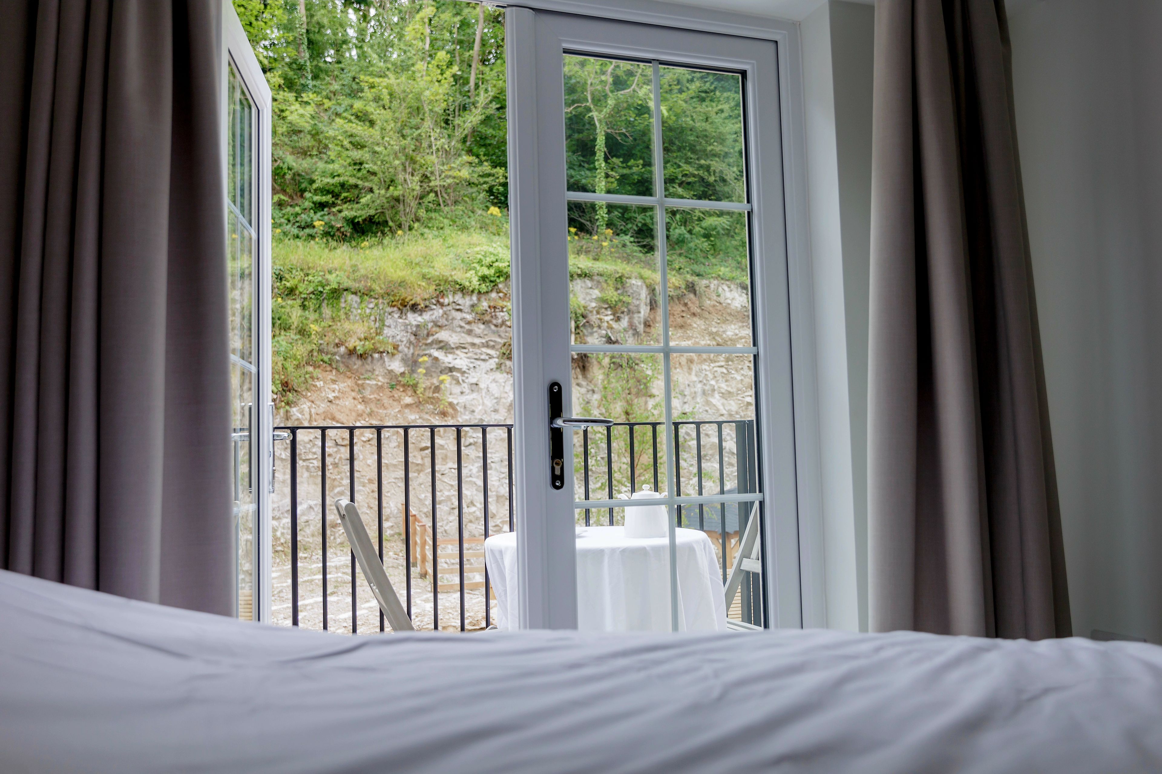 Ein Hotelzimmer mit einem Bett, einem Tisch mit Stuhl und einem Balkon mit Geländer.