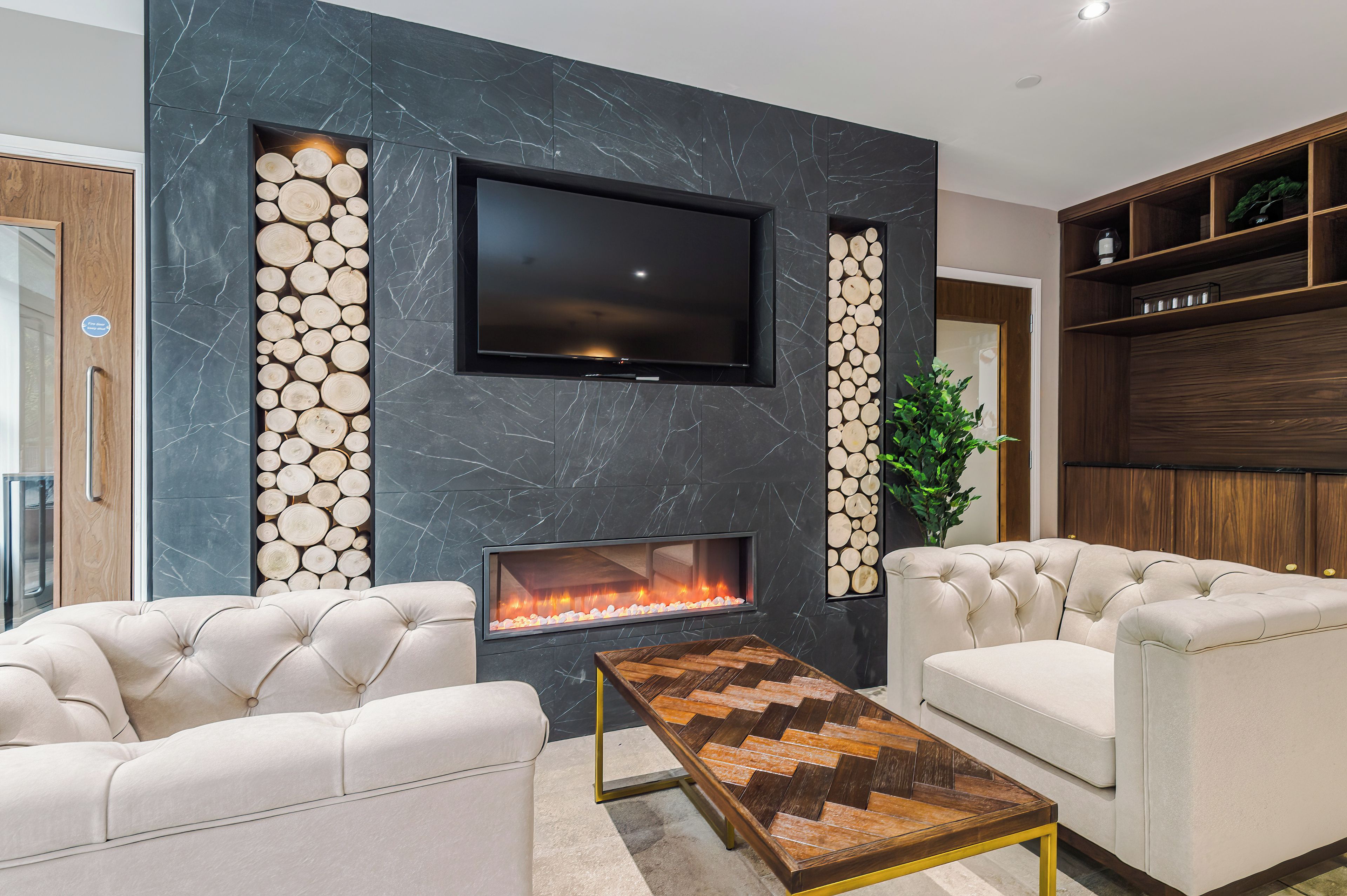 A modern living room with a flat-screen TV, a fireplace, and two sofas.