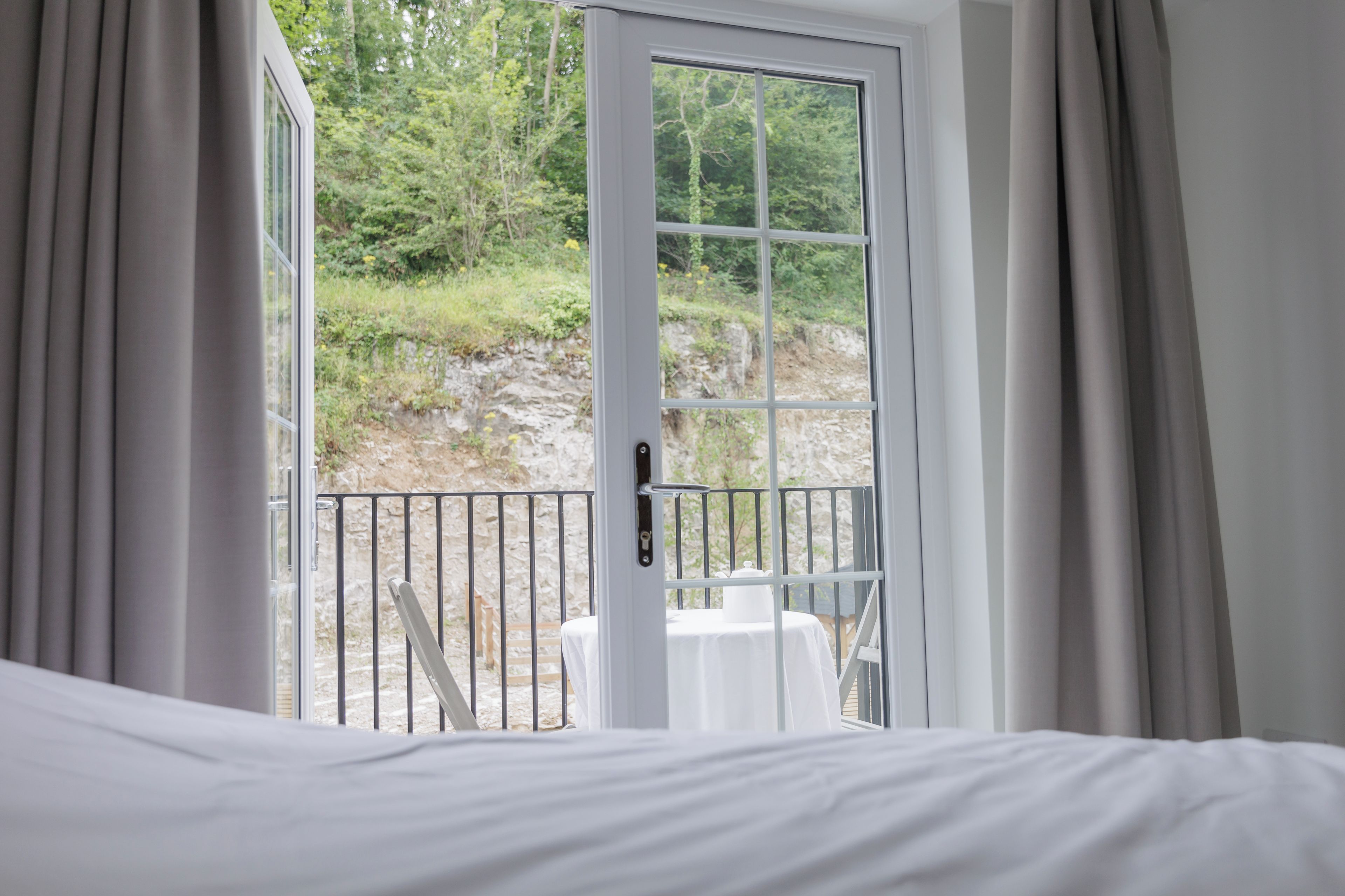 Une chambre avec un lit, une table blanche et un balcon doté d’une balustrade.