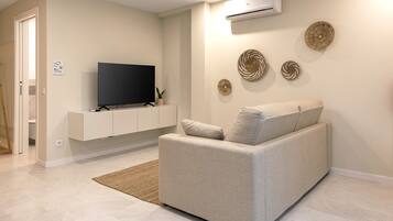 A modern living room with a sofa, a flat-screen TV, and decorative wall art.