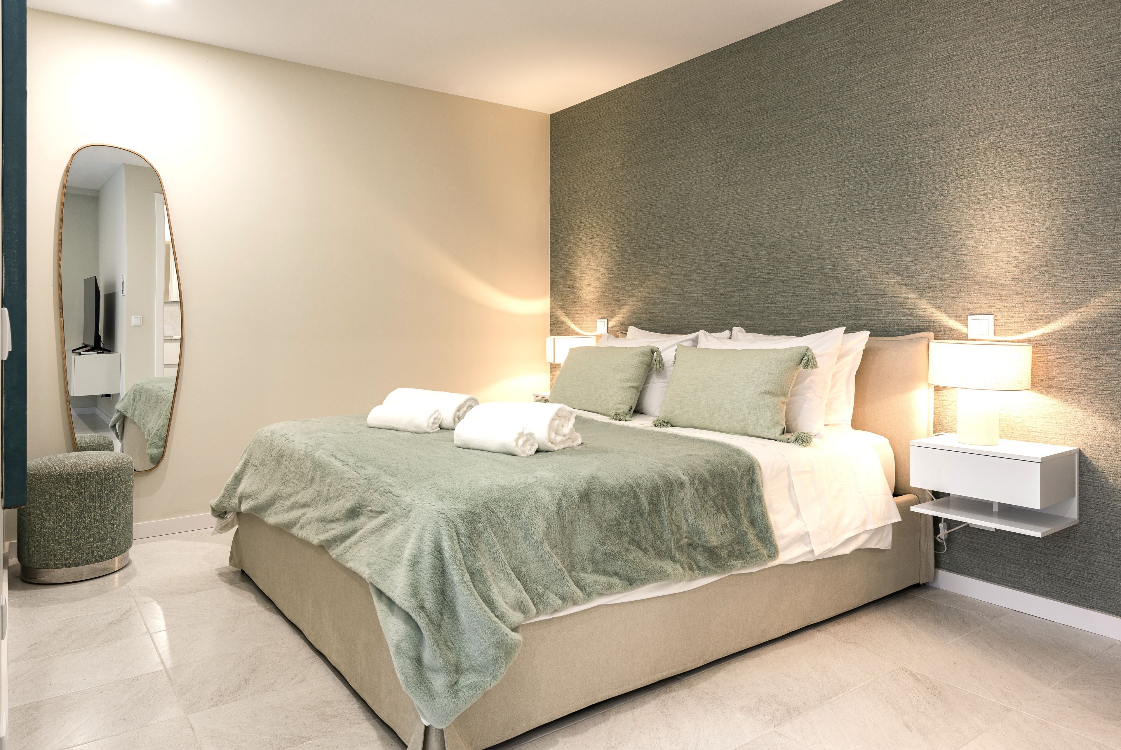 Serene king bedroom with accent wall, soft lighting & fresh linens