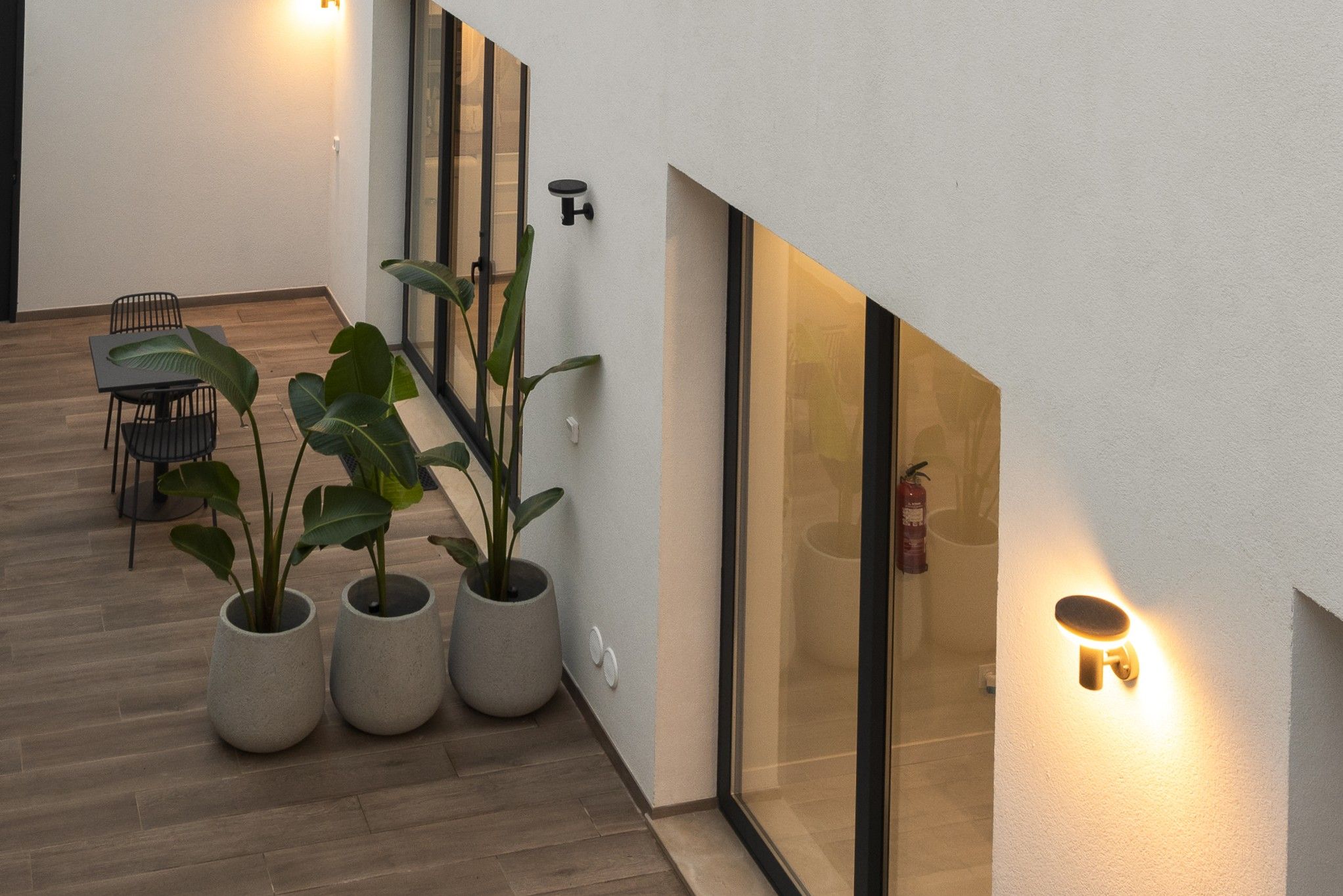 Een modern interieur met een houten vloer, een eethoek met stoelen en potplanten.