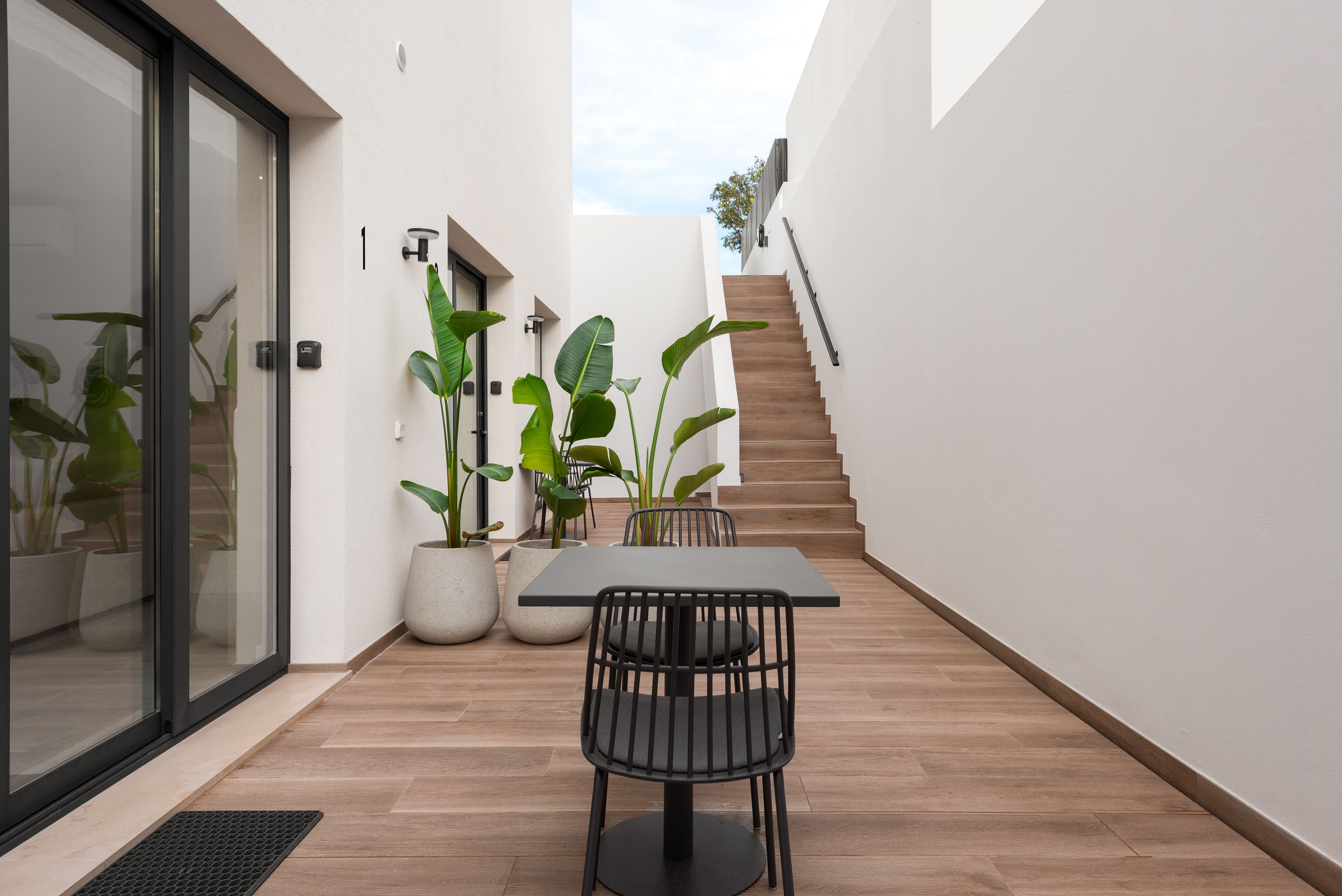 Sleek courtyard with dining set, tropical plants, and stair to terrace