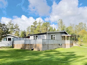 Ein modernes, zweistöckiges Haus mit eingezäunter Garten und einer Holzterrasse.