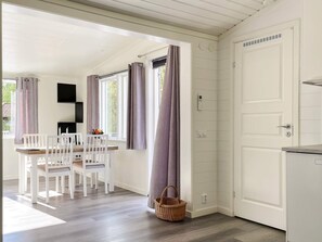 Ein Zimmer mit Esstisch, Stühlen, einer Küchenzeile und einer Tür.