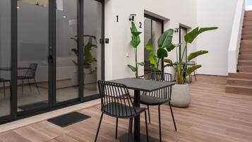 An outdoor patio area with a table and chairs, potted plants, and a staircase.