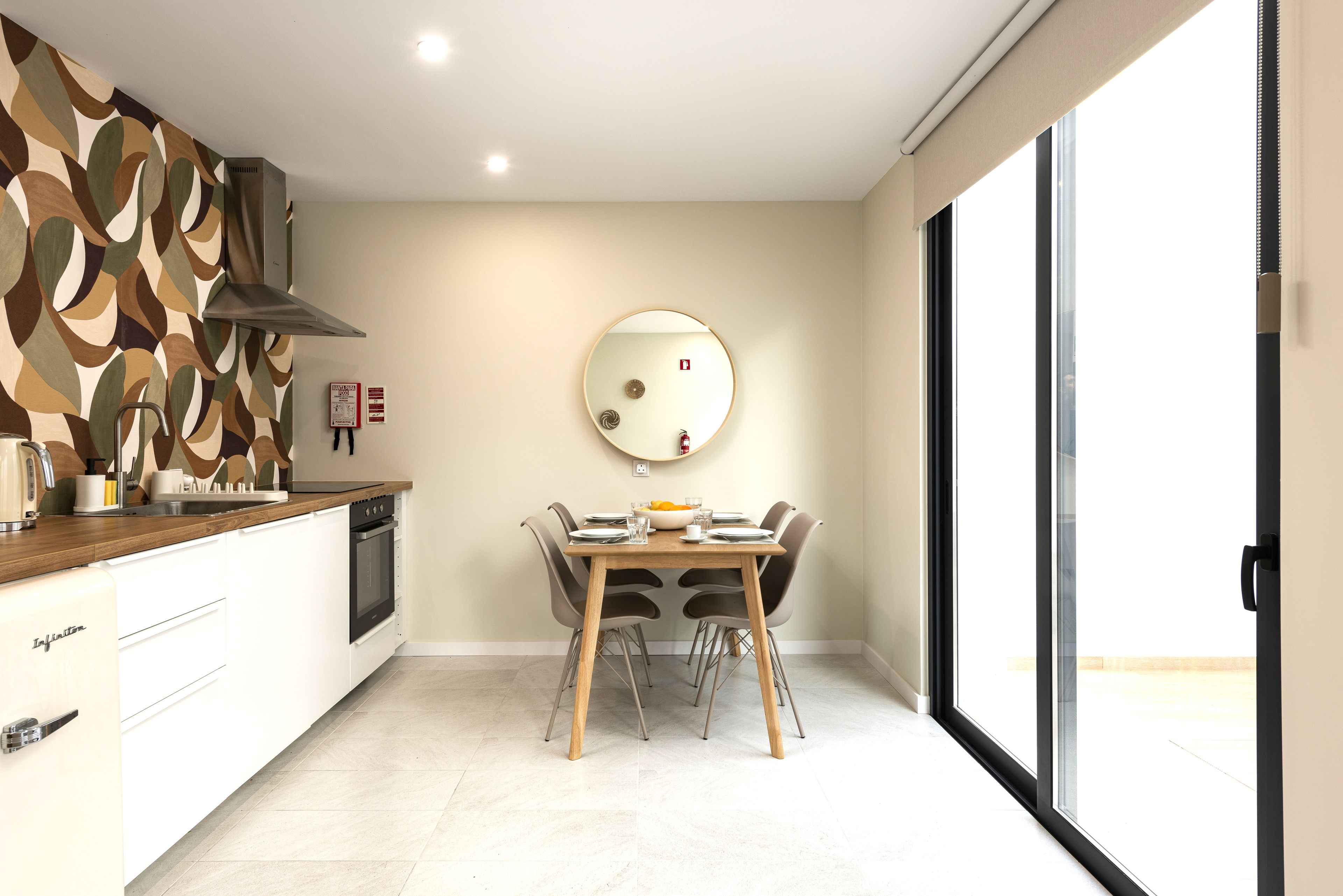 Una cocina moderna con comedor, un espejo redondo y una ventana.