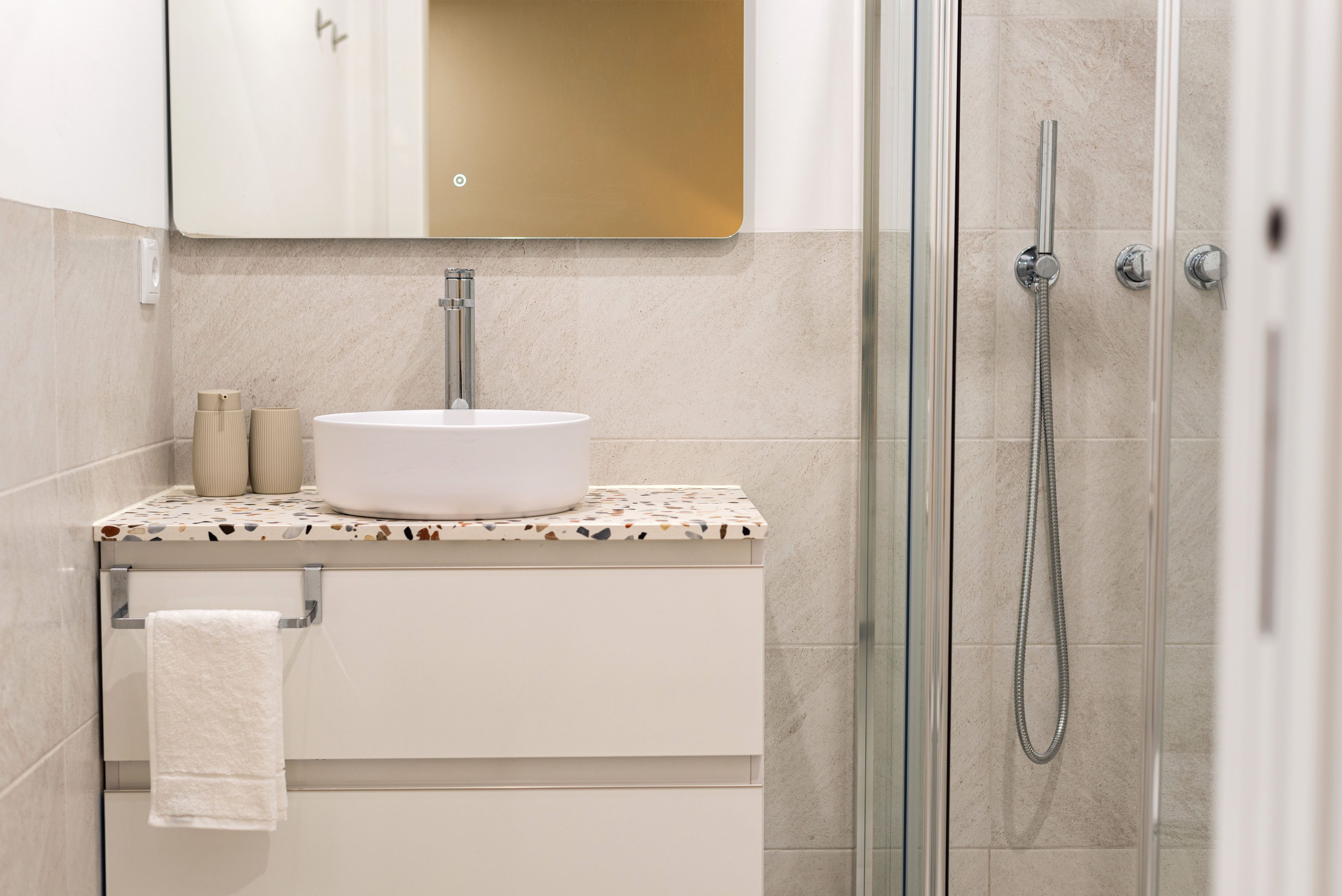 A bathroom with a white sink, a mirror above it, and a shower area with a glass door.