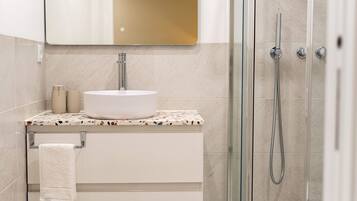 A bathroom with a white sink, a mirror above it, and a shower area with a glass door.