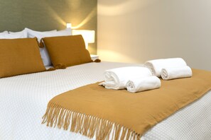 A neatly made bed with a white quilt, two rolled white towels, and a brown throw blanket. - Villa 41 Faro Airport | Studio 2 | 4 Guests | Early/Late Flights (Faro)
