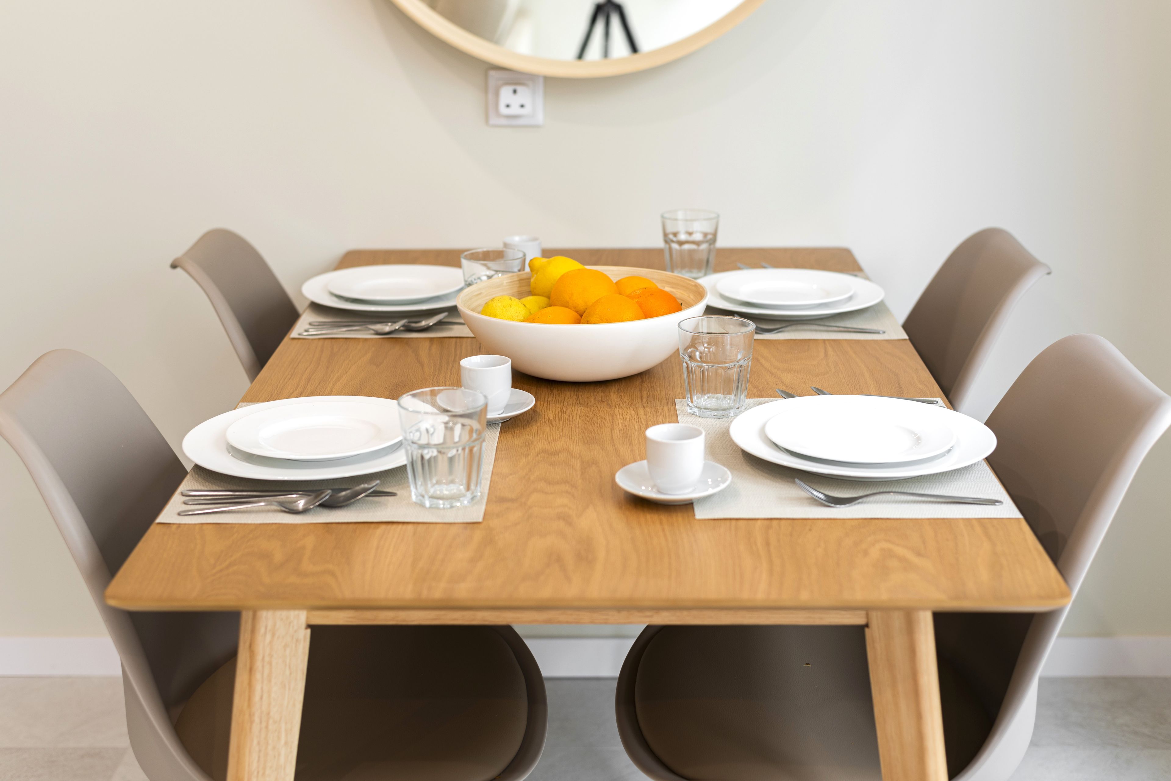 Bright 4-seat dining nook with wood table, sleek chairs, and citrus centerpiece.