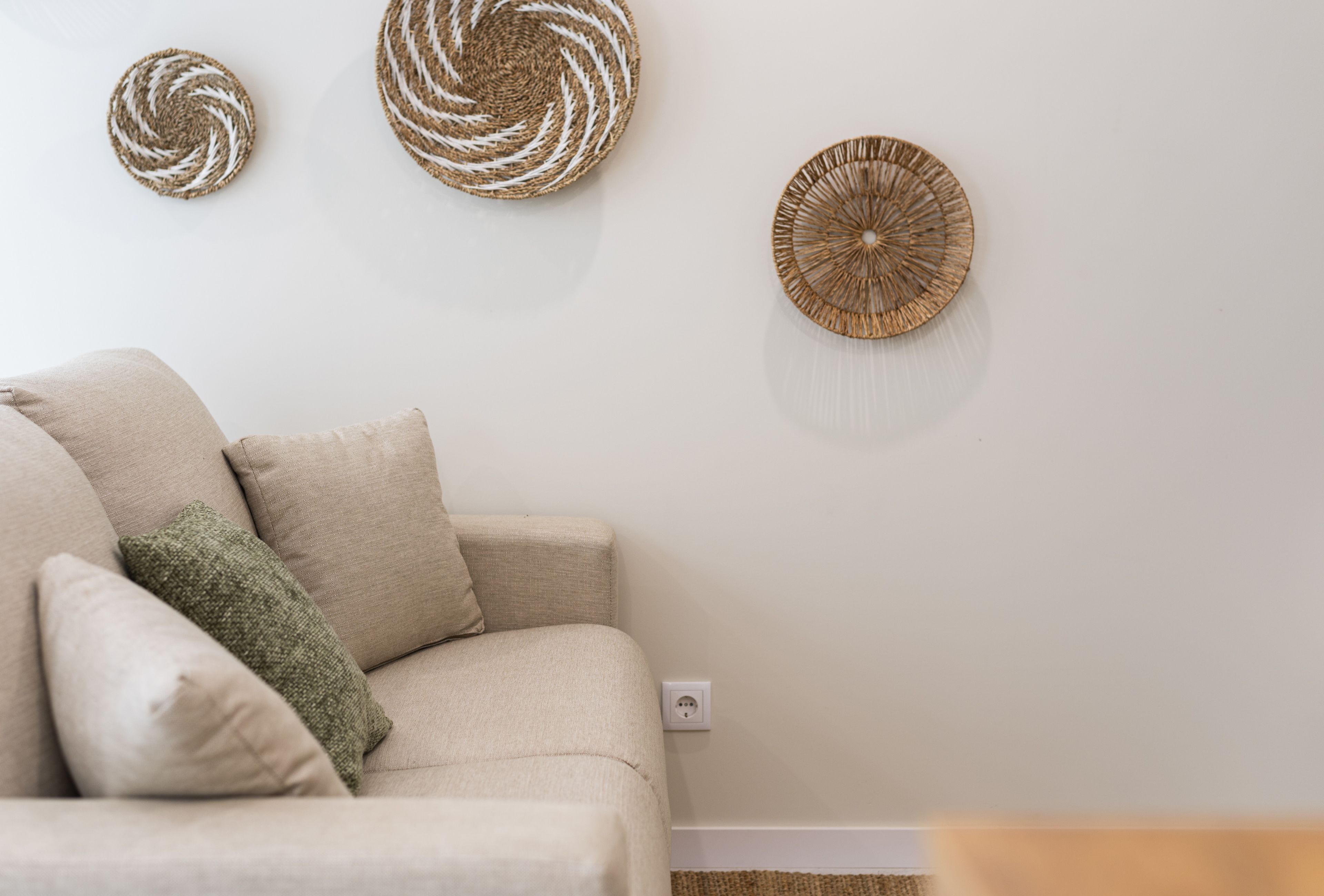 Cozy neutral lounge with woven wall art, plush sofa, and earthy textures.