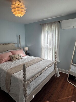 A bedroom with a wooden bed, a nightstand, a lamp, a window with curtains, and a ceiling light fixture. - Something Blue: New-to-market 2-bedroom peaceful retreat (Nevada)