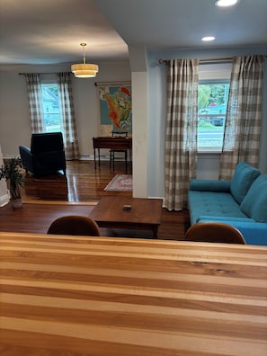 Una sala de estar con un sofá azul, una mesa de centro de madera y un comedor con una mesa y sillas de madera.