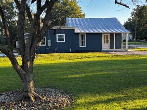 A house with a sloped metal roof, a front door, and a small front yard with a tree and a gravel path. - Something Blue: New-to-market 2-bedroom peaceful retreat (Nevada)