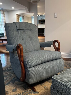 A houndstooth patterned armchair with wooden armrests and legs, positioned in a living room with a visible kitchen area in the background. - Something Blue: New-to-market 2-bedroom peaceful retreat (Nevada)