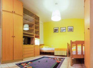 A bedroom with a bed, a wooden wardrobe, a shelf unit, and a hanging light fixture. - Lovely studio in perfect location (Split)