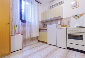 A compact kitchen with a refrigerator, stove, and a window with curtains. - Lovely studio in perfect location (Split)