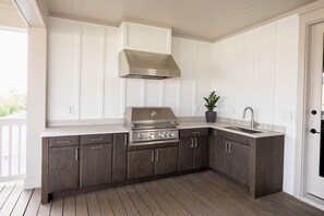 A kitchen with a built-in grill, a sink, and wooden cabinets. - NEW! Spacious Home, 3rd Fl Patio and Bar w/ Costal View! (Panama City)