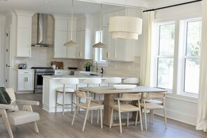 Een moderne keuken met witte kasten, een centraal eiland en hanglampen.