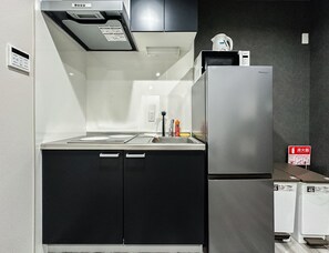 Eine Küche mit einem Edelstahlkühlschrank, einer Mikrowelle und einem Herd. Es gibt Schränke und ein Spülbecken.