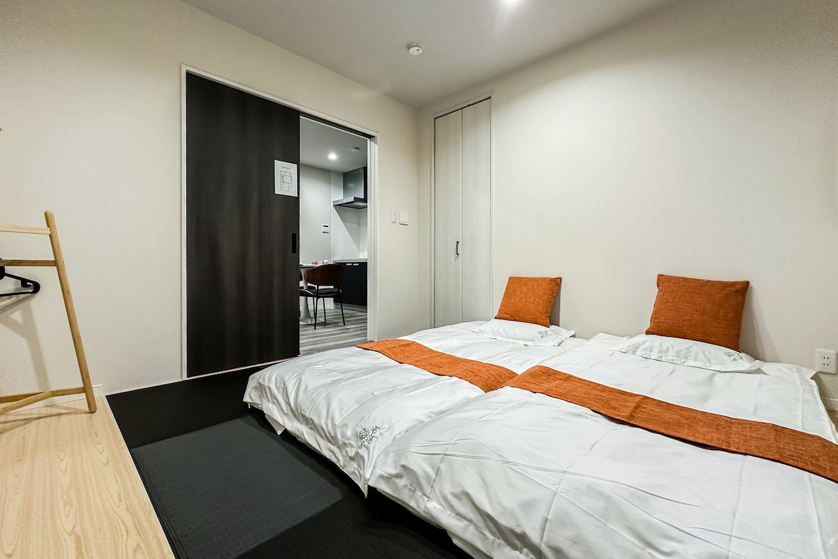 Ein Hotelzimmer mit einem Bett, einem Holzstuhl, einem Schreibtisch und einem Kleiderschrank.