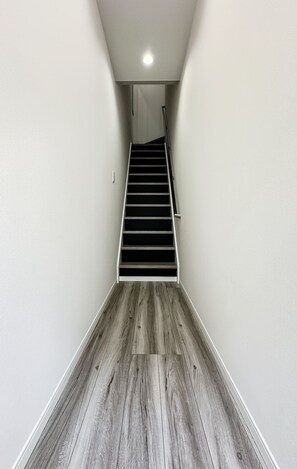 Eine enge Holztreppe führt zu einer kleinen Plattform mit einer Tür.