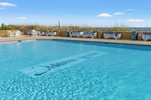 A swimming pool with lounge chairs and a lifeguard stand. - Maisons-Sur-Mer 1602 Ocean View 2BR- Outdoor Pool (Myrtle Beach)