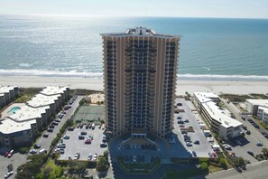 A high-rise hotel with a central courtyard, parking, and a view of the beach. - Maisons-Sur-Mer 1602 Ocean View 2BR- Outdoor Pool (Myrtle Beach)