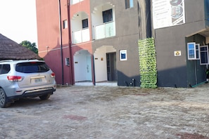 Ein Gebäude mit einem gepflasterten Innenhof, einem parkenden Auto und einer Bar mit einem Schild.