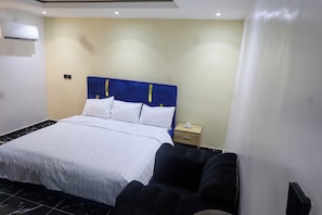 Ein Hotelzimmer mit Bett, Nachttisch und Wand-Klimaanlage.