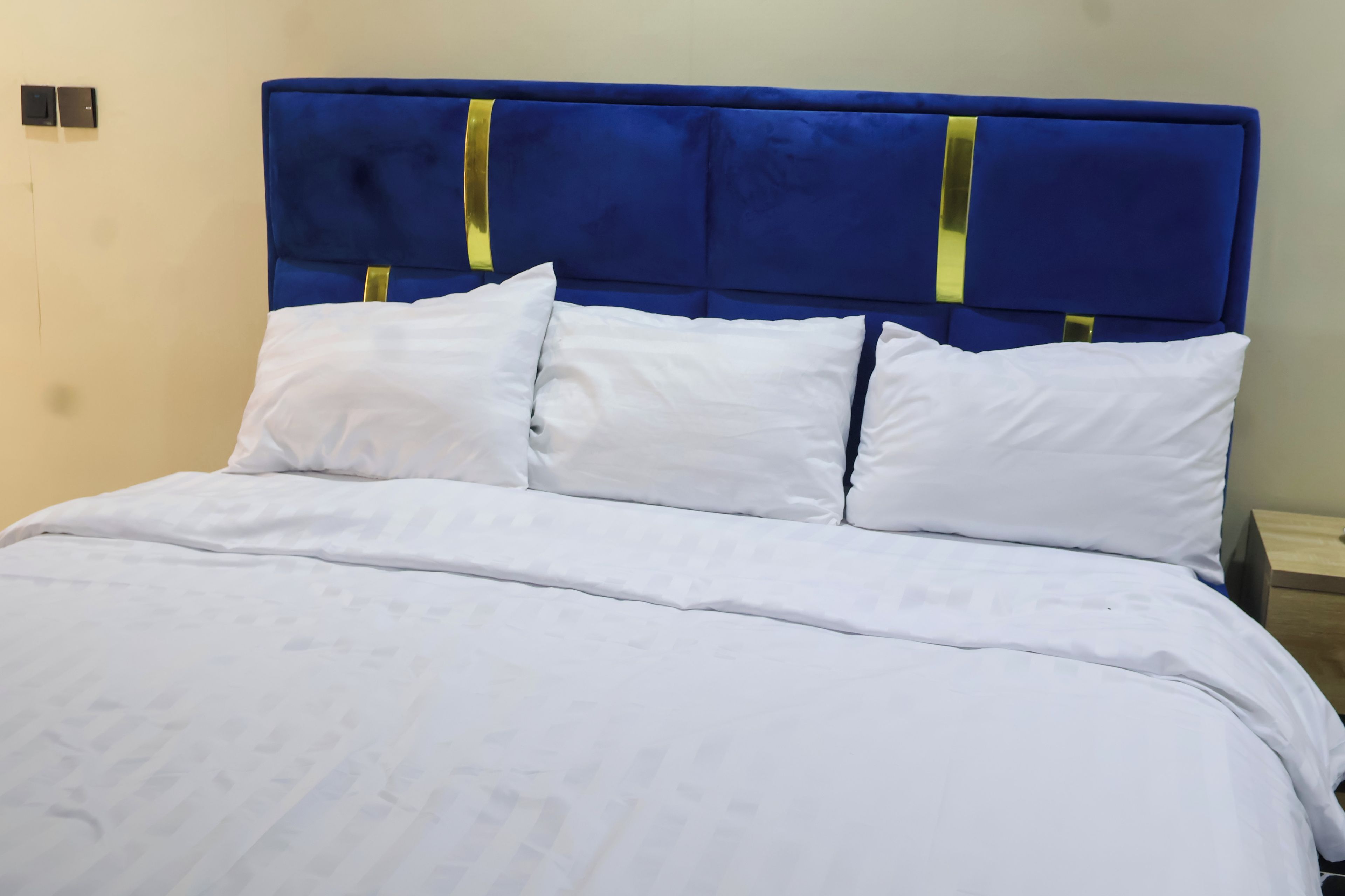 A bed with a blue headboard and white bedding.
