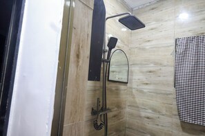 Ein Badezimmer mit Dusche, Spiegel und einem karierten Handtuch.