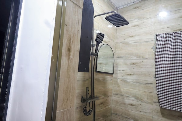 A bathroom with a shower, a mirror, and a checkered towel.