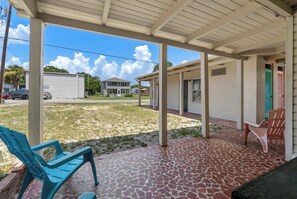 A covered outdoor area with a tiled floor, two chairs, and a bench. - Rustic Eight Bedroom Beach House Steps from the Ocean (North Myrtle Beach)