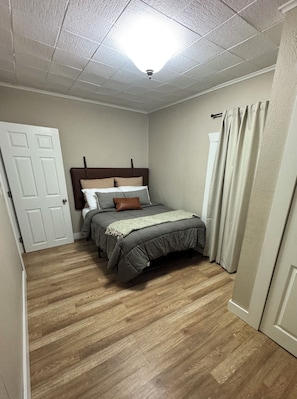 A bedroom with a bed, a door, a window with curtains, and a ceiling light. - Villa M, a cozy home with firepit, few blocks away from town square (Humboldt)