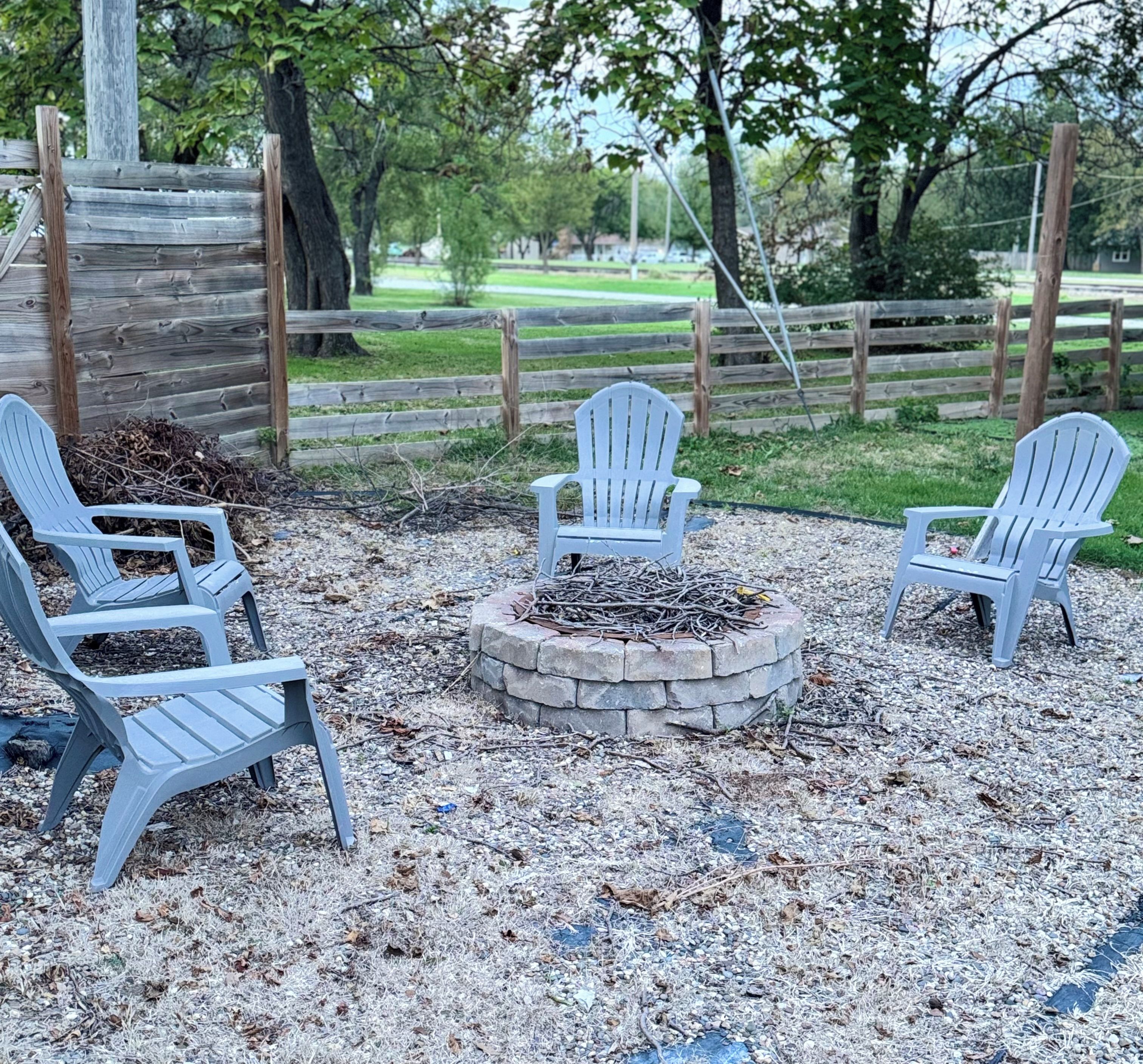 Un foyer extérieur entouré de quatre chaises Adirondack.