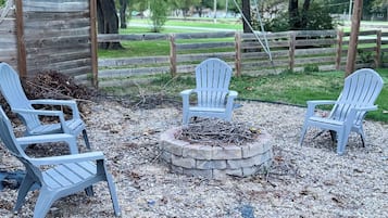 Un foyer extérieur entouré de quatre chaises Adirondack.