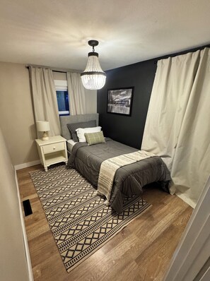 Un dormitorio con cama, mesita de noche, lámpara y candelabro.