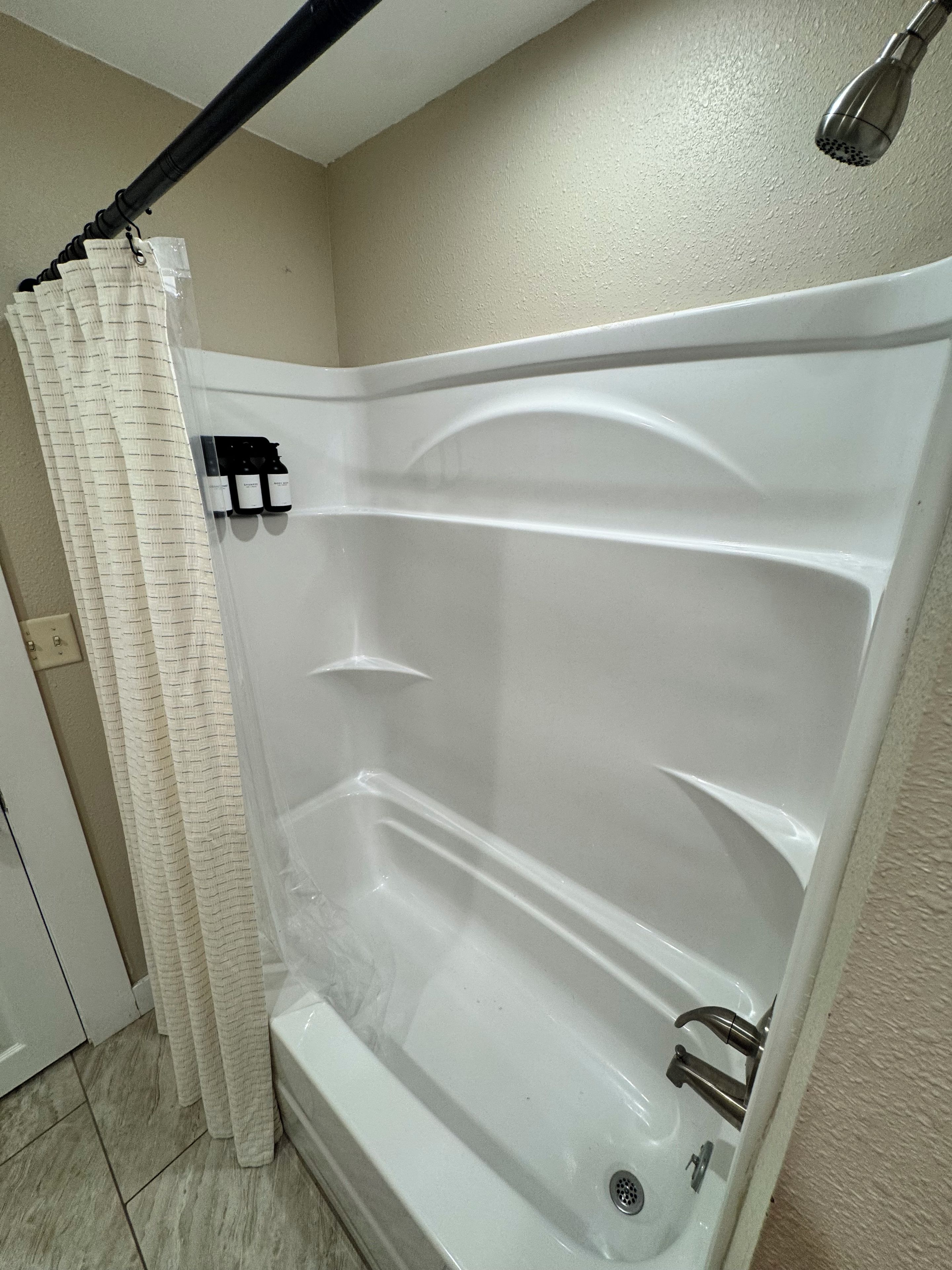 A bathtub with a showerhead, a curtain, and a faucet.