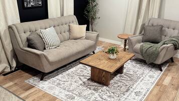 Un salon avec un canapé beige, une table basse en bois et un tapis à motifs.