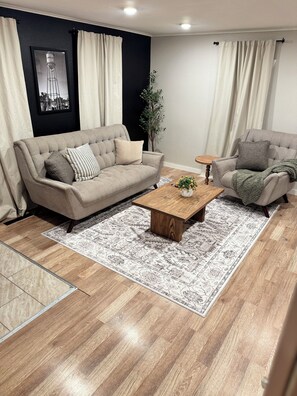 A living room with a beige sofa, a wooden coffee table, and a patterned rug. - Villa M, a cozy home with firepit, few blocks away from town square (Humboldt)