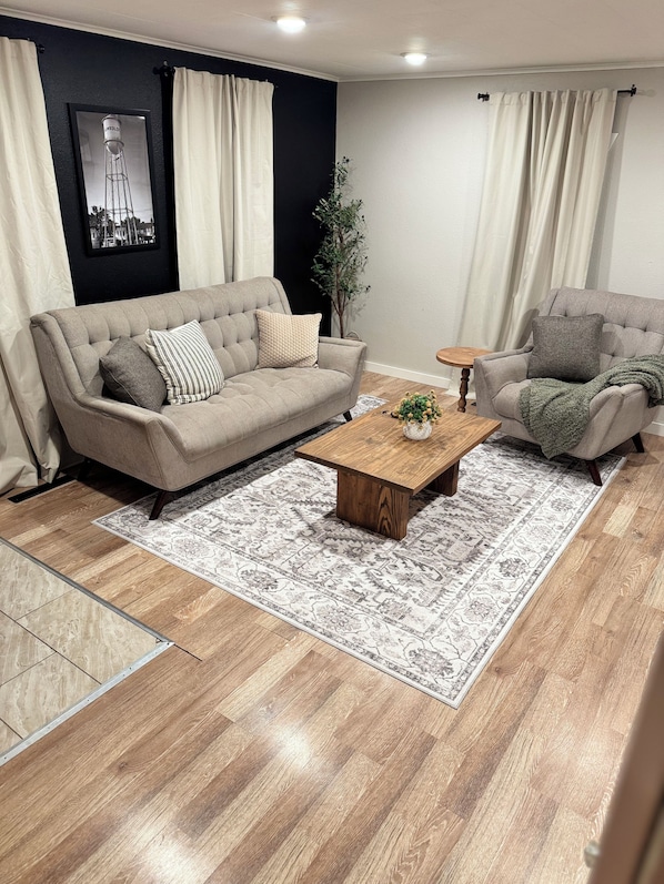 A living room with a beige sofa, a wooden coffee table, and a patterned rug.