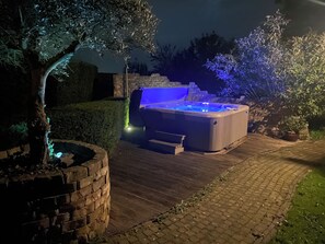 A hot tub with a stone wall and a brick planter, surrounded by a paved patio. - Knus chalet met privé jacuzzi tussen Hoorn en Enkhuizen (Wijdenes)